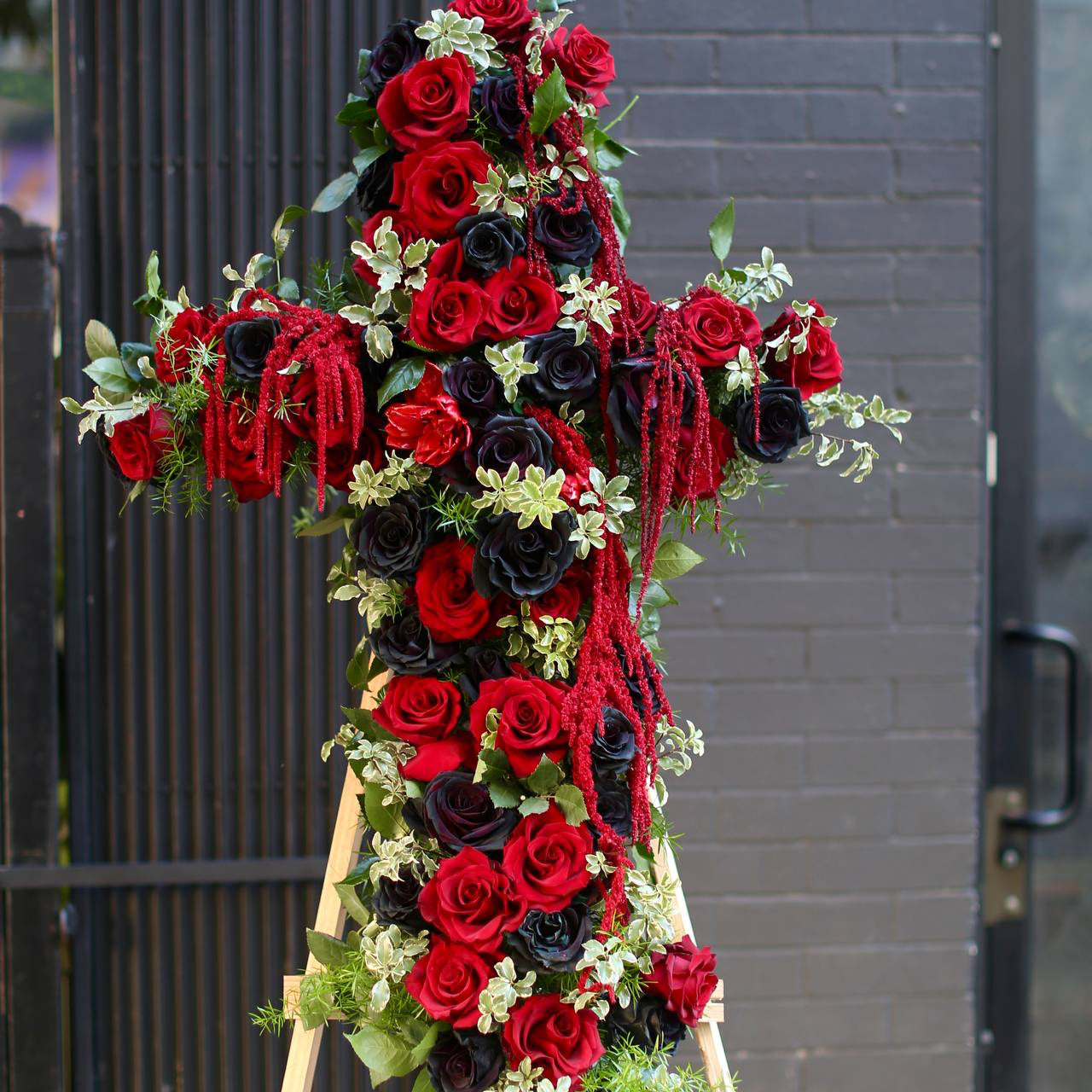 Handcrafted sympathy arrangement showcasing a floral cross design, ideal for honoring cherished memories