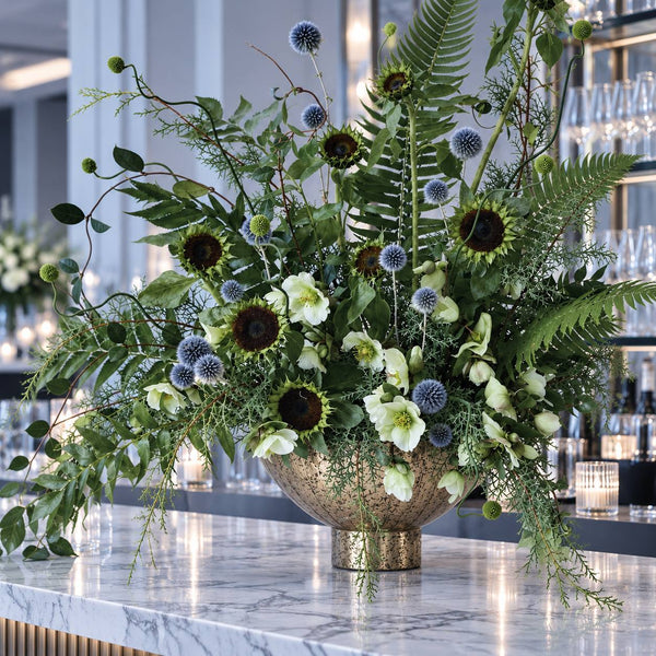 Sunflower and thistle statement in brass bowl on hotel bar, Los Angeles