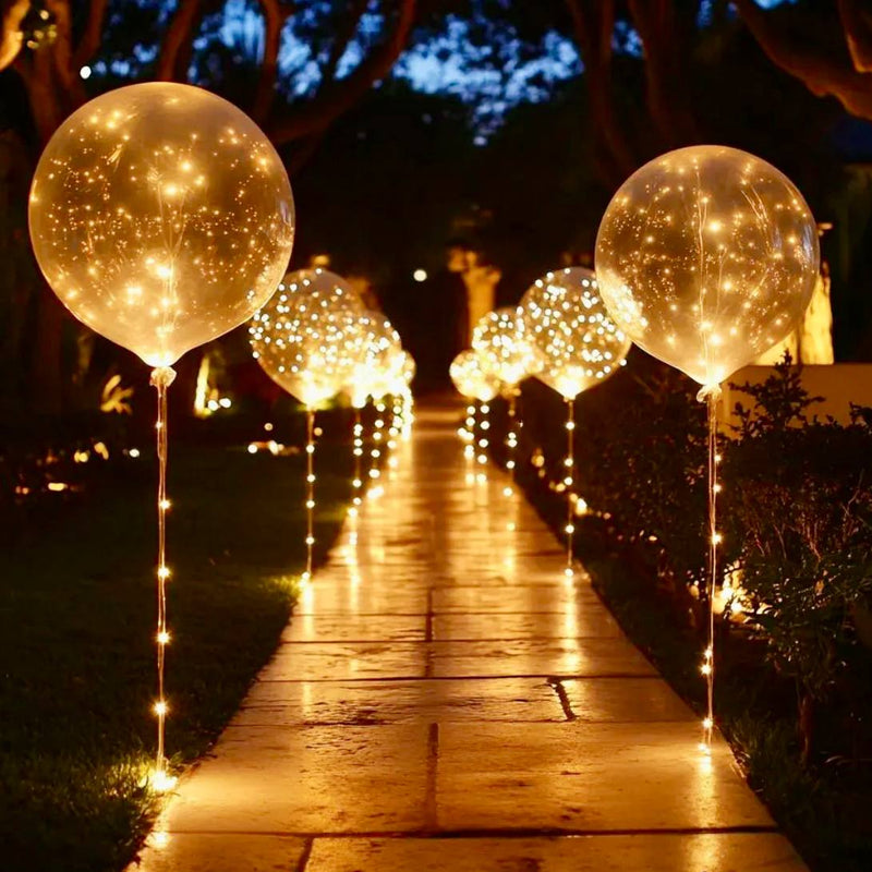 Garden pathway lined with clear LED-light filled balloon orbs and warm candle ground lights for Los Angeles outdoor proposal setup.