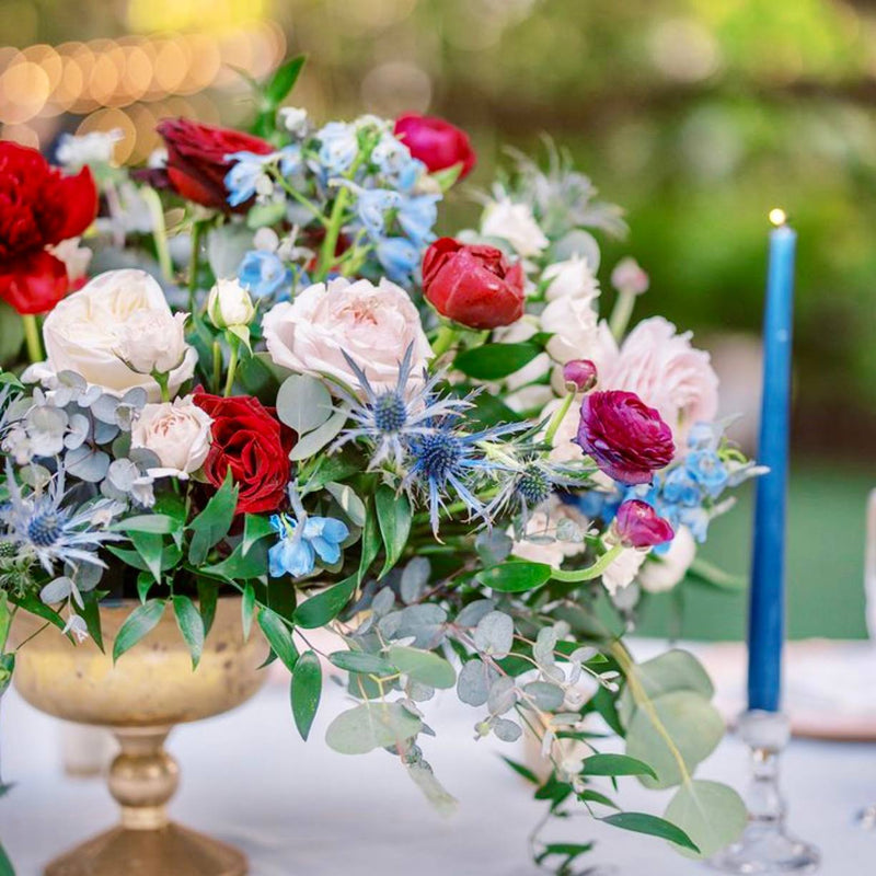 Red, white, and blue 4th of July compote centerpiece with garden roses, ranunculus, blue delphinium, and eryngium thistle for Los Angeles delivery.