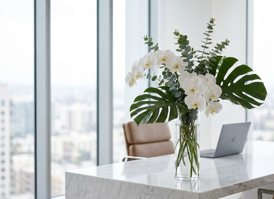 modern architectural arrangement of white orchids and greenery on a marble office desk in Los Angeles