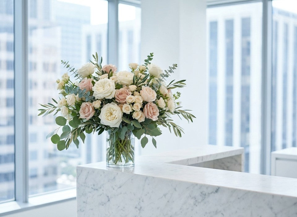 fresh white and blush rose arrangement at its peak on a marble office reception desk in Los Angeles
