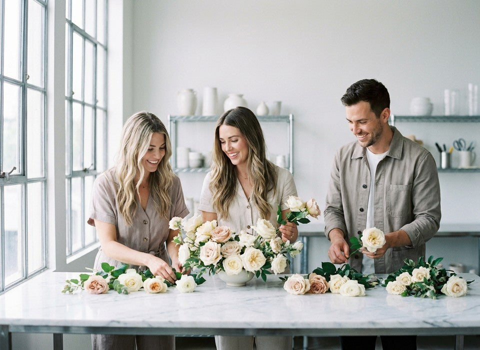 corporate team arranging white and blush roses together at a floral workshop in Los Angeles