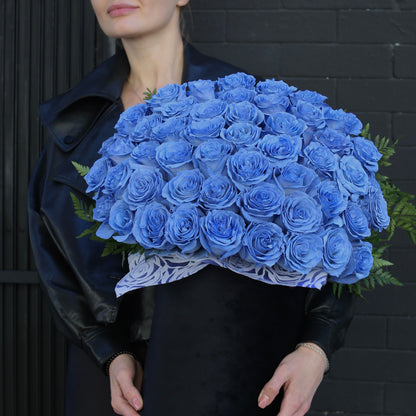 Close-up of velvety Light Blue Roses with dewy petals, accented by eucalyptus leaves in a hand-tied bouquet.