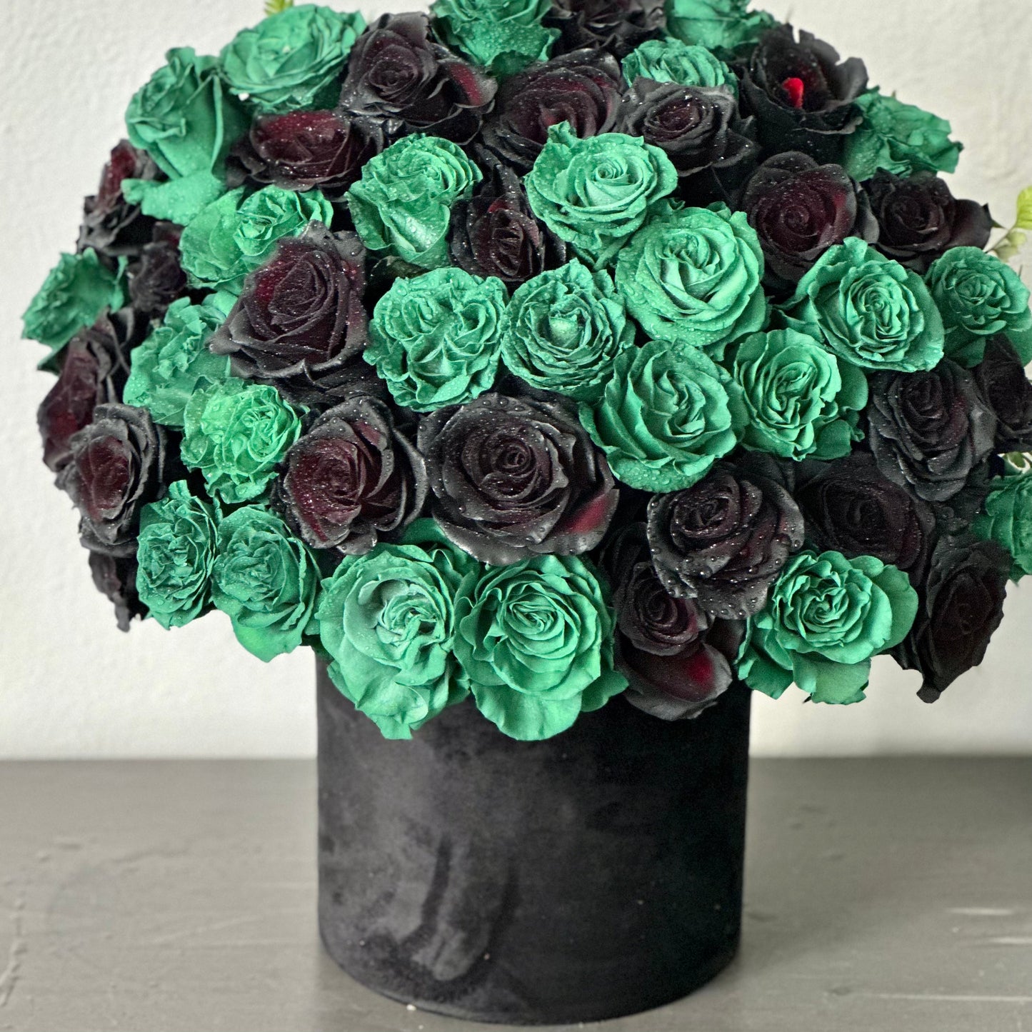 Elegant floral arrangement featuring rich roses, crisp lilies, and seasonal greens arranged in a clear glass vase, radiating sophistication.