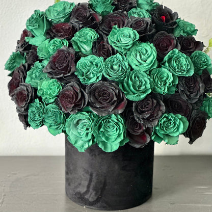 Elegant floral arrangement featuring rich roses, crisp lilies, and seasonal greens arranged in a clear glass vase, radiating sophistication.