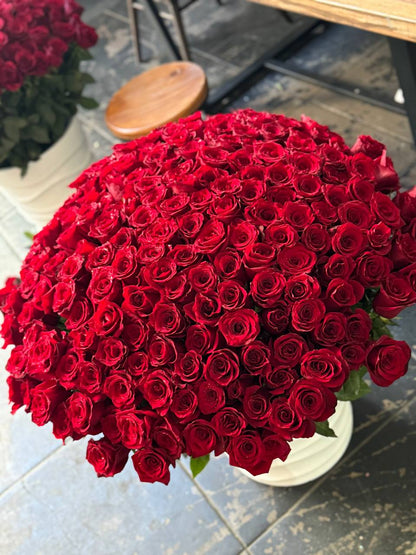 Luxurious cascade of 200 red roses spilling from a modern ceramic vase, symbolizing grand romance