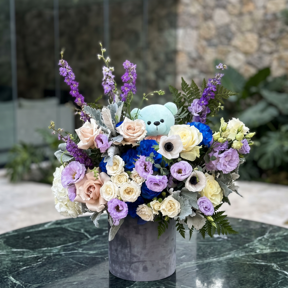 Babyblossom: Pink Clover's lush blue teddy bear arrangement with peach, cream, blue roses, purple lis