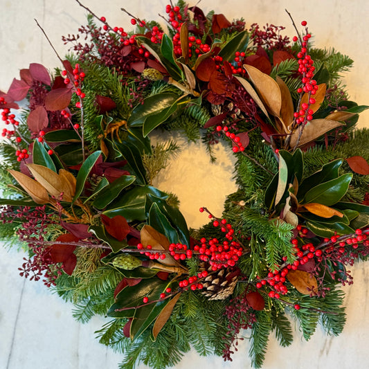 Elegant holiday wreath with seasonal greenery and red accents, ideal for festive celebrations