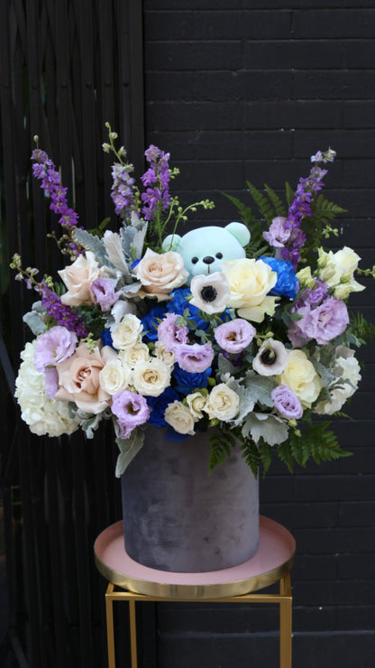 Vibrant Royal Blue Roses paired with soft pink Eustoma and delicate Delphinium blooms in a glass vase.
