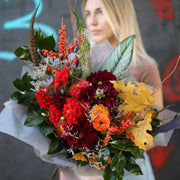 Vibrant autumn bouquet featuring red dahlias, orange berries and seasonal greenery, styled in a natural, rustic arrangement