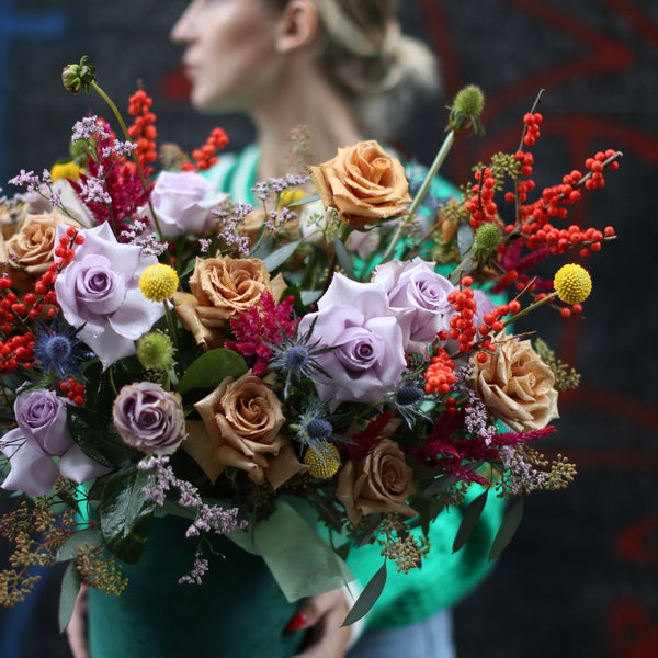 Vibrant autumn floral arrangement featuring warm-toned roses and seasonal blooms in a stylish decorative vase
