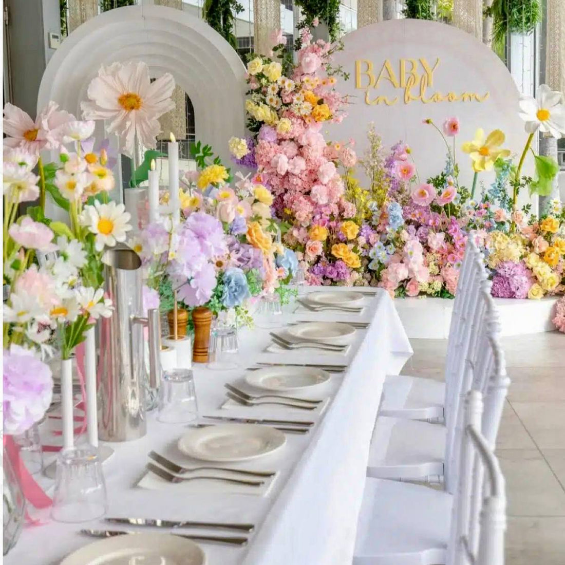 Colorful pastel baby shower backdrop with floral pillars, paper flowers, and head table florals across the arch for Los Angeles event delivery.