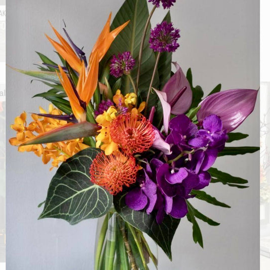 Vibrant tropical bouquet with bird of paradise, magenta vanda orchids, orange pincushion protea, yellow mokara orchids, and anthurium for Los Angeles delivery.