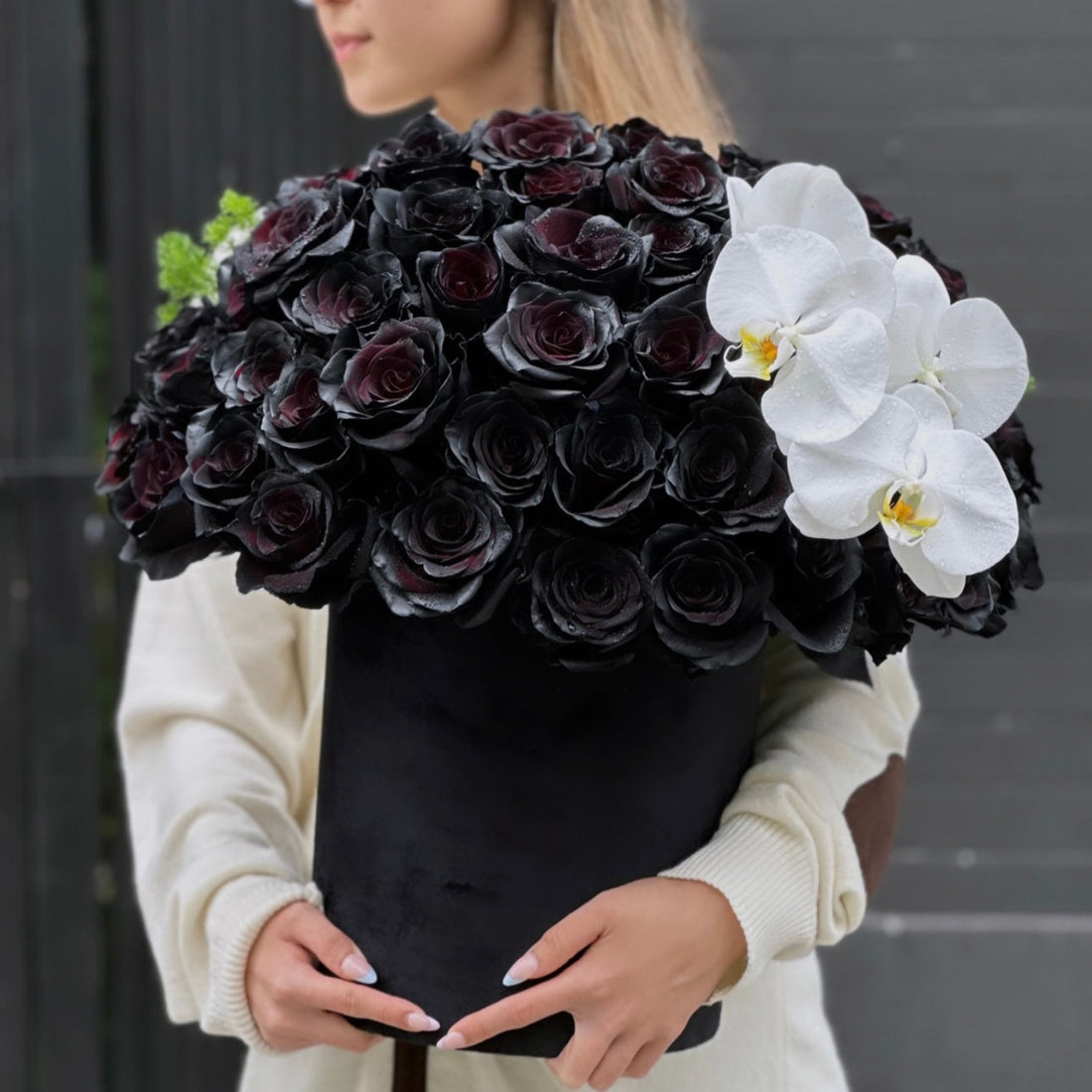 Black roses and white orchids in a精致 keepsake box, surrounded by lush greenery – a bold and elegant floral arrangement from Pink Clover LA.
