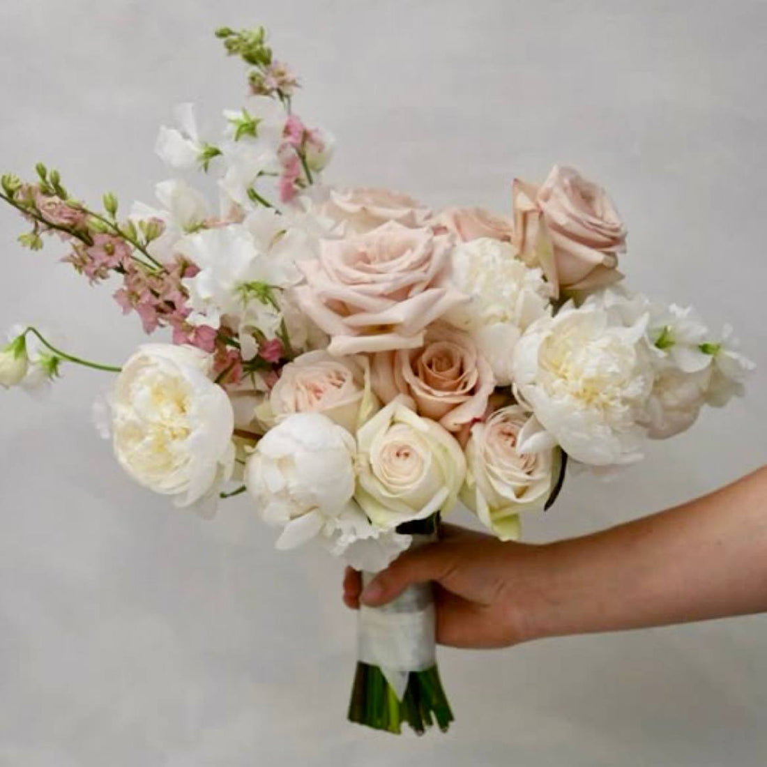 Blush and white bridal bouquet with peonies, roses, and pink larkspur in Los Angeles
