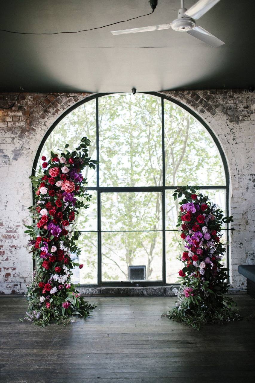 Modern asymmetrical wedding arch with cascading orchids and textured greenery