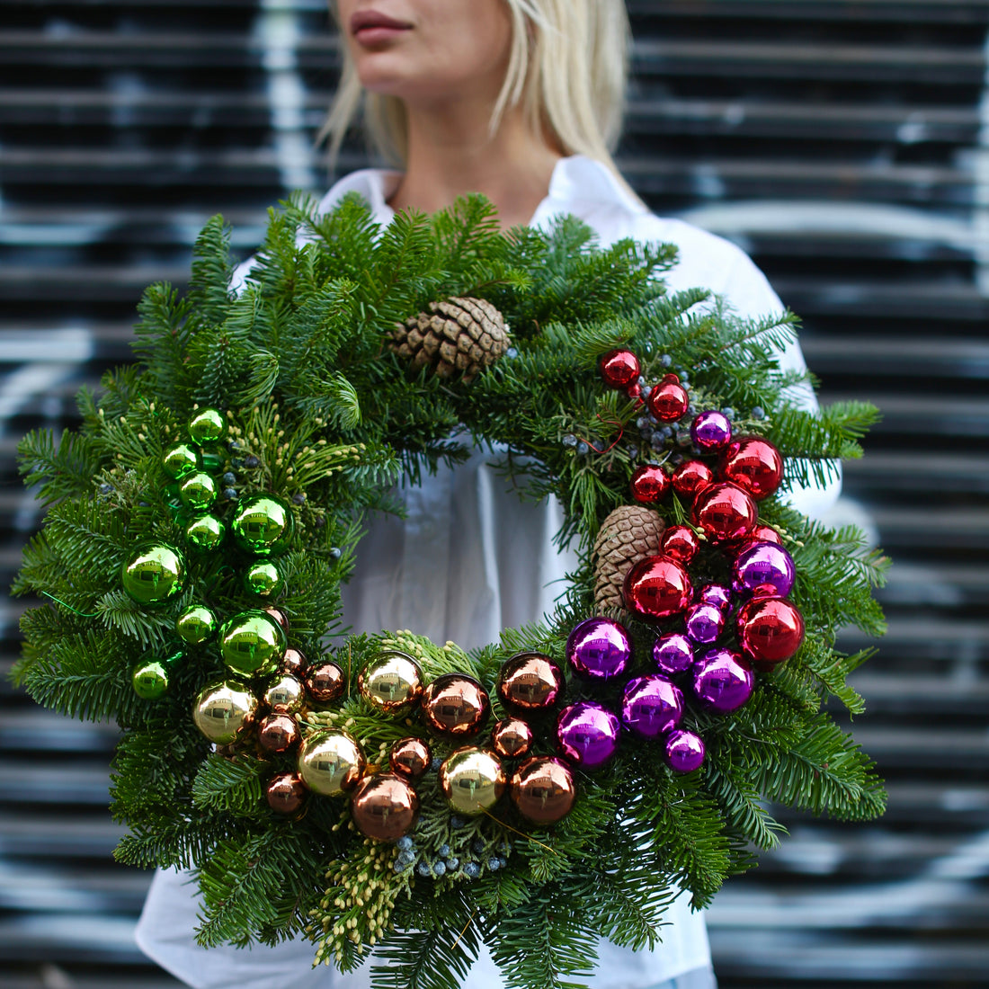 Fresh Christmas pine wreath with red berries, pinecones and colorful decorations – perfect for luxury holiday gifting