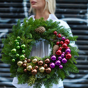 Fresh Christmas pine wreath with red berries, pinecones and colorful decorations – perfect for luxury holiday gifting