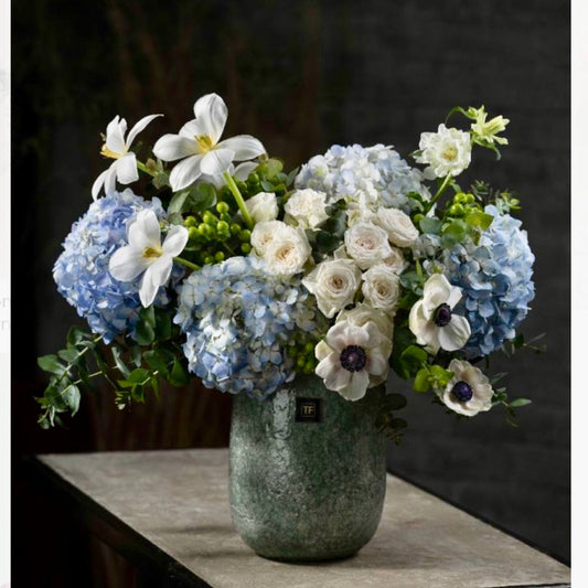 Hanukkah arrangement with blue hydrangea, white anemones, cream garden roses, white tulips, and eucalyptus in a textured green-gray ceramic vase for Los Angeles delivery.