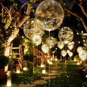 Garden proposal setup with clear LED-light orb balloons hanging from trees and warm pillar candle lanterns lining the path for Los Angeles outdoor proposal.