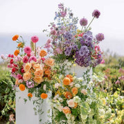 Garden romance pedestal flower collection with peach roses and lavender blooms for outdoor events by Pink Clover Flowers Los Angeles