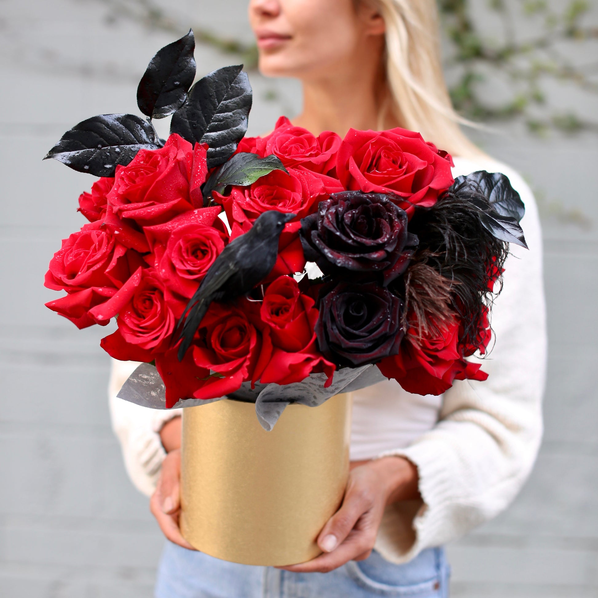 Dramatic Halloween bouquet featuring red roses, black blooms, feathers & raven decor in a luxury keepsake box – ideal for premium gifting