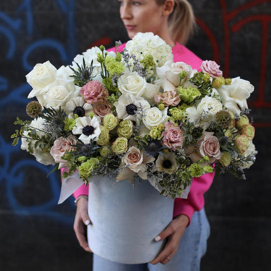 Elegant flower arrangement in a decorative box featuring anemones, roses and greenery, styled for luxury gifting