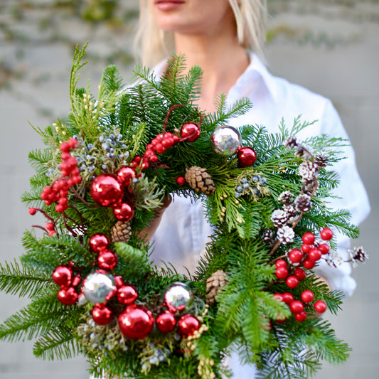 Fresh Christmas wreath with red berries, pinecones and festive decorations – perfect for luxury holiday gifting