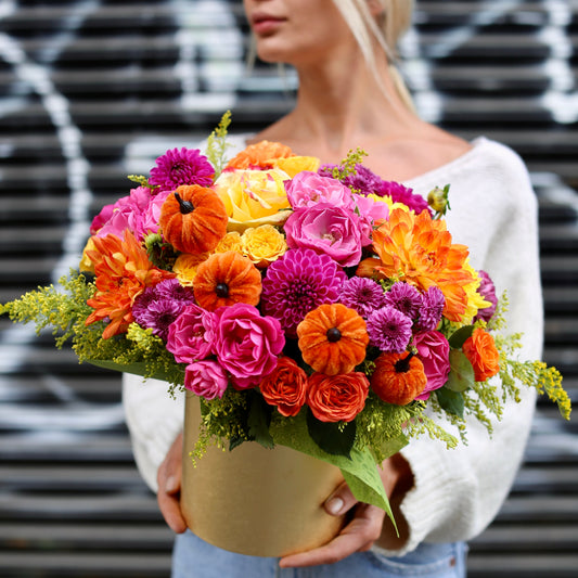 Vibrant autumn floral arrangement featuring roses, mums, gerberas and greenery in a decorative pumpkin-themed keepsake box