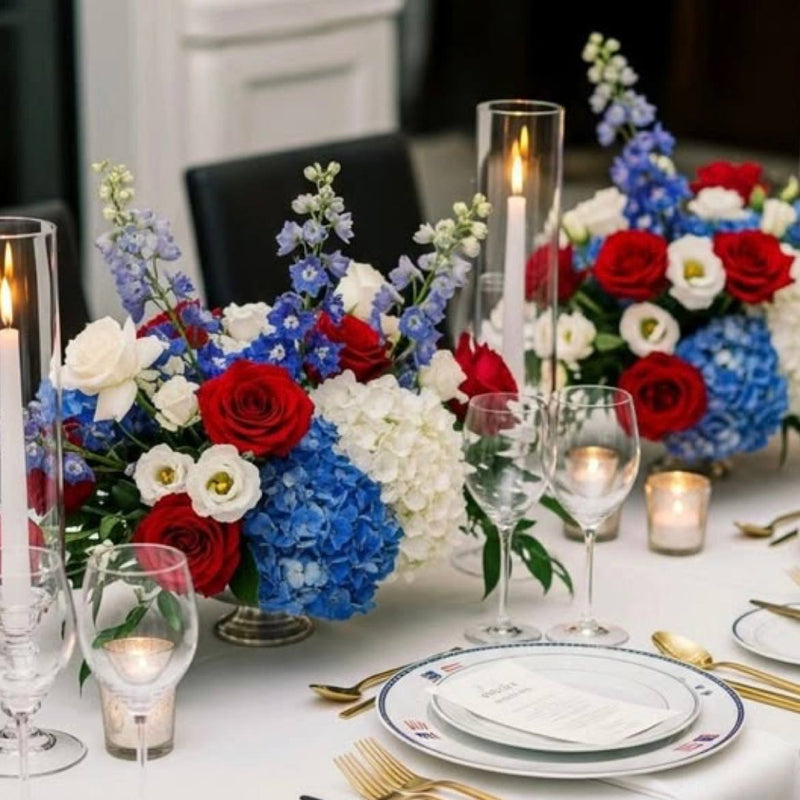Pair of red, white, and blue 4th of July compote centerpieces with red roses, blue hydrangea, white hydrangea, and lisianthus for Los Angeles event delivery.
