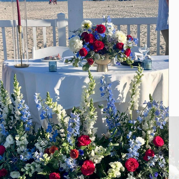4th of July sweetheart table setup on Santa Monica beach with red, white, and blue centerpiece, cand