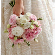 Pink and ivory bridal bouquet with lisianthus, roses, and dahlias against a lace wedding dress in Los Angeles