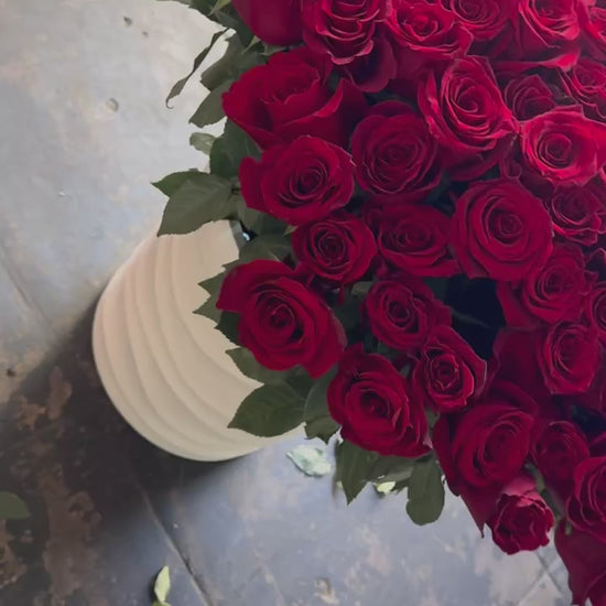 Voluminous red rose arrangement with cascading blooms and a sleek ceramic base, ideal for luxury gifting