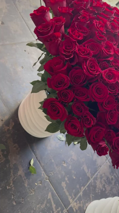 Voluminous red rose arrangement with cascading blooms and a sleek ceramic base, ideal for luxury gifting