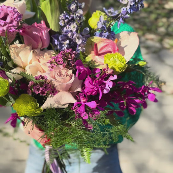 Soft pink and white floral arrangement with lush foliage, presented in a delicate wrap for a premium gifting style
