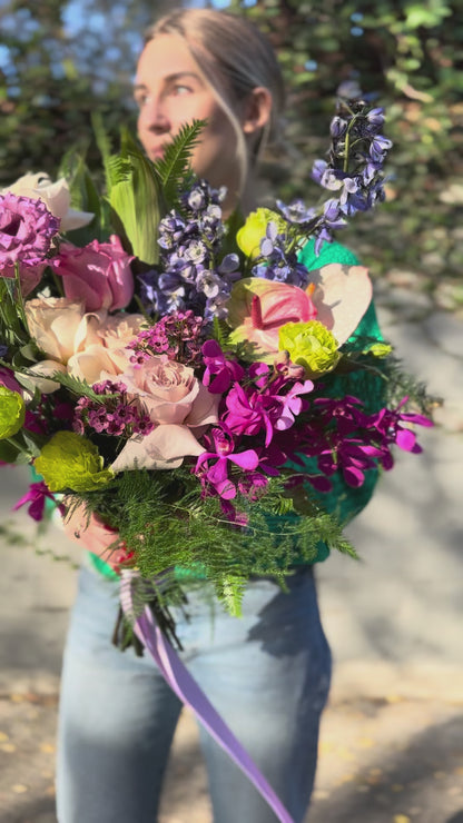 Soft pink and white floral arrangement with lush foliage, presented in a delicate wrap for a premium gifting style