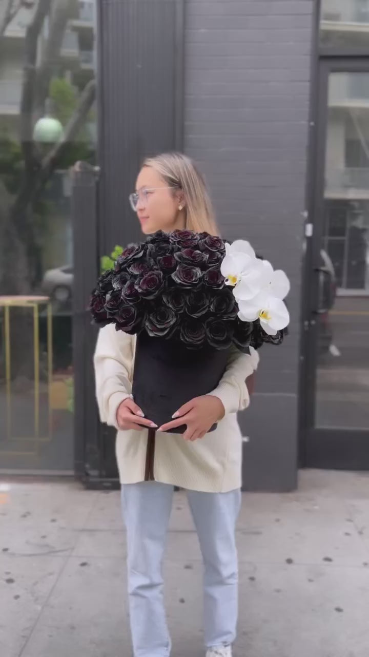 Luxury flower arrangement featuring dark velvet roses and exotic orchids, perfectly styled in a精致 gift box for special occasions.