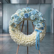 Blue and white rose sympathy wreath on easel, Los Angeles funeral flower delivery