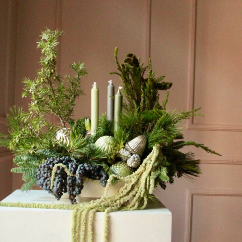 Modern sage green Christmas centerpiece with evergreens, juniper, pinecones, sage taper candles, and dried amaranthus for Los Angeles delivery.