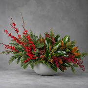 Snowberry Christmas arrangement with red winterberry and magnolia in a stone bowl, delivered in Los 