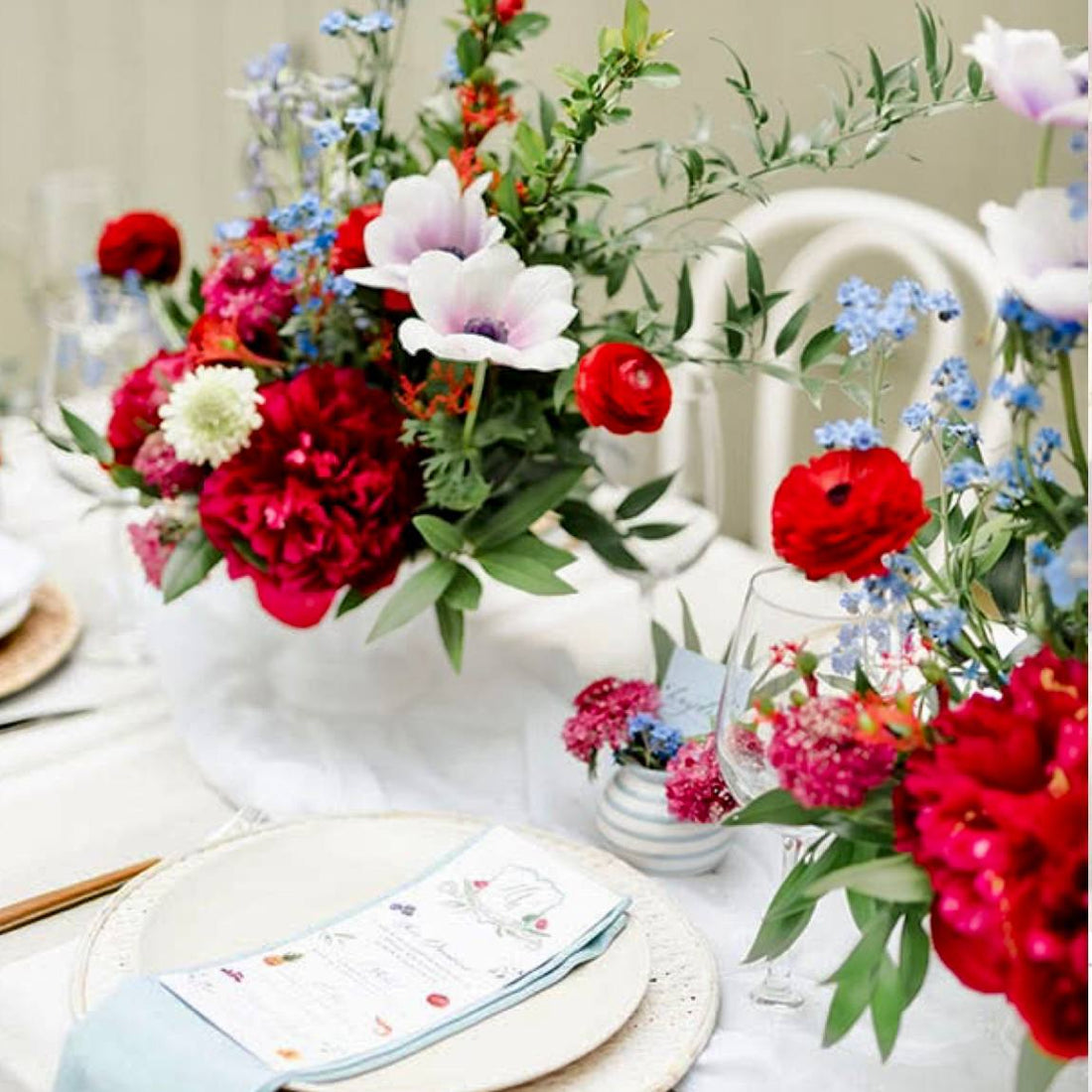 4th of July centerpiece with white anemones, red peonies, blue forget-me-nots, and red ranunculus in a white compote vase for Los Angeles delivery.