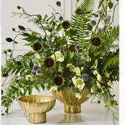 Modern corporate statement arrangement with chocolate sunflowers, blue echinops thistle, hellebores, and ferns in an antique brass compote for Los Angeles delivery.