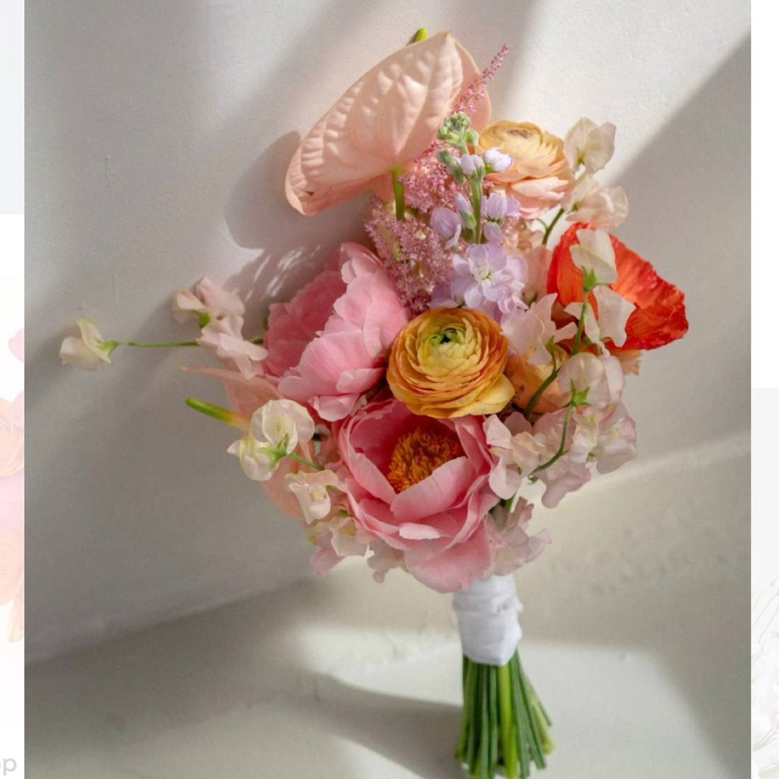 Colorful bridal bouquet with pink peonies, orange ranunculus, red poppies, and pink anthurium in Los Angeles