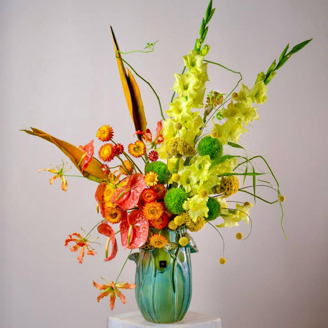 Luxury tropical flower arrangement with gladiolus anthuriums and gloriosa lilies in designer teal vase by Pink Clover Flowers Los Angeles