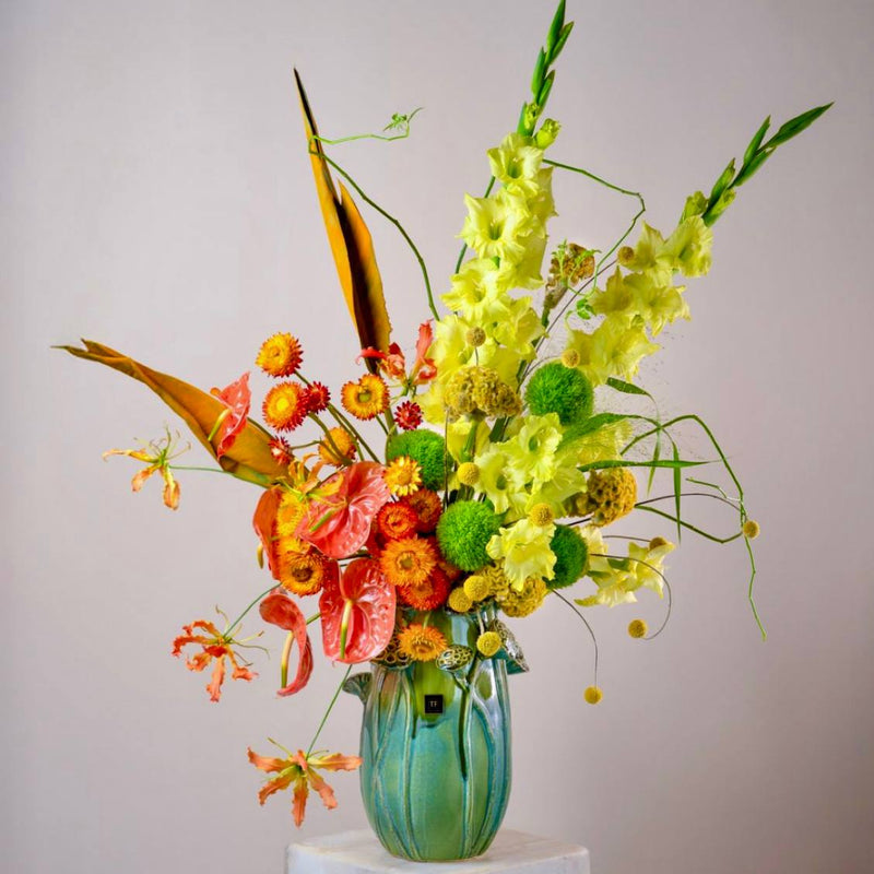 Luxury tropical flower arrangement with gladiolus anthuriums and gloriosa lilies in designer teal vase by Pink Clover Flowers Los Angeles