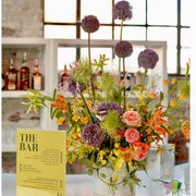 Vibrant garden bar centerpiece with purple alliums and orange ranunculus for Los Angeles events
