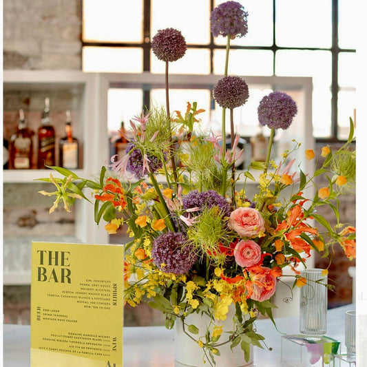 Vibrant garden bar centerpiece with purple alliums and orange ranunculus for Los Angeles events
