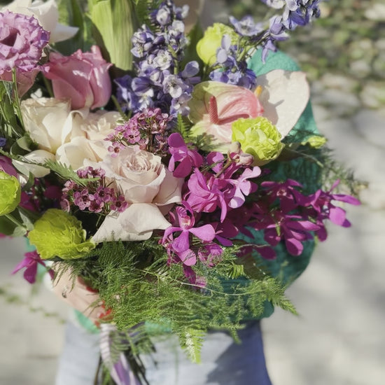 Soft pink and white floral arrangement with lush foliage, presented in a delicate wrap for a premium gifting style