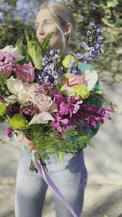 Soft pink and white floral arrangement with lush foliage, presented in a delicate wrap for a premium gifting style